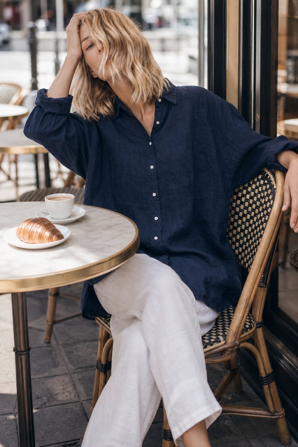 Woman in a navy oversized linen shirt at a café terrace with an espresso