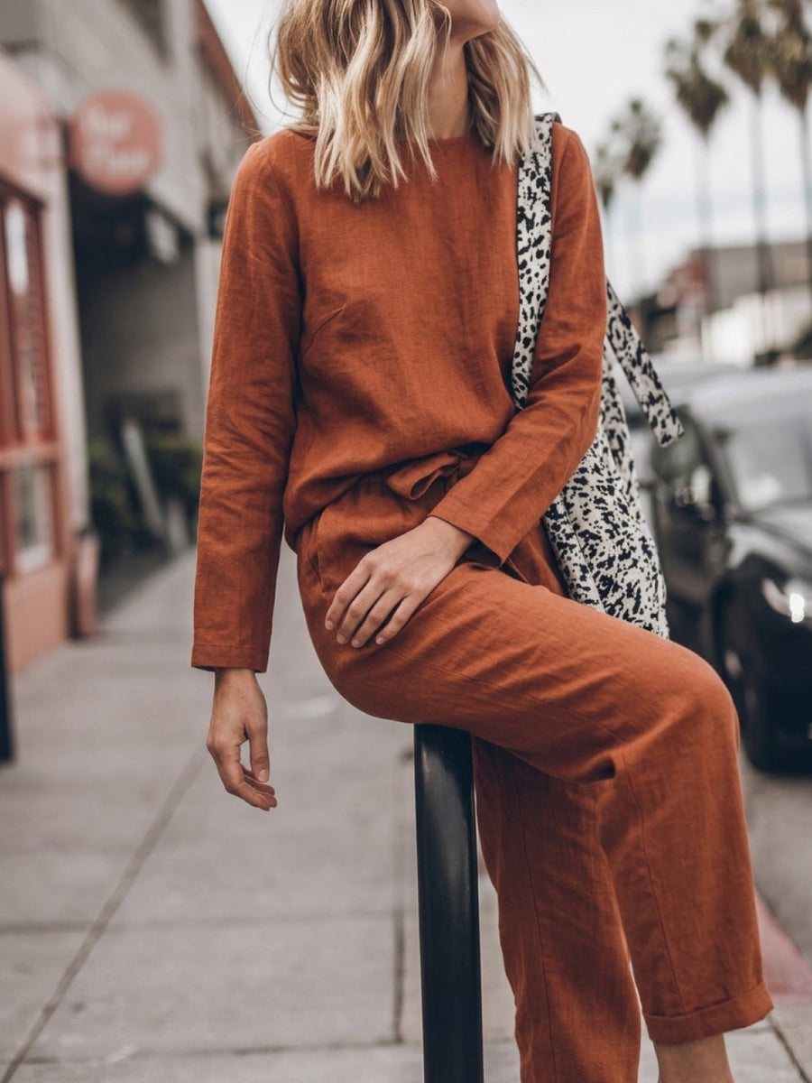 Woman walking in a rusty orange cotton-linen set in bright sunlight