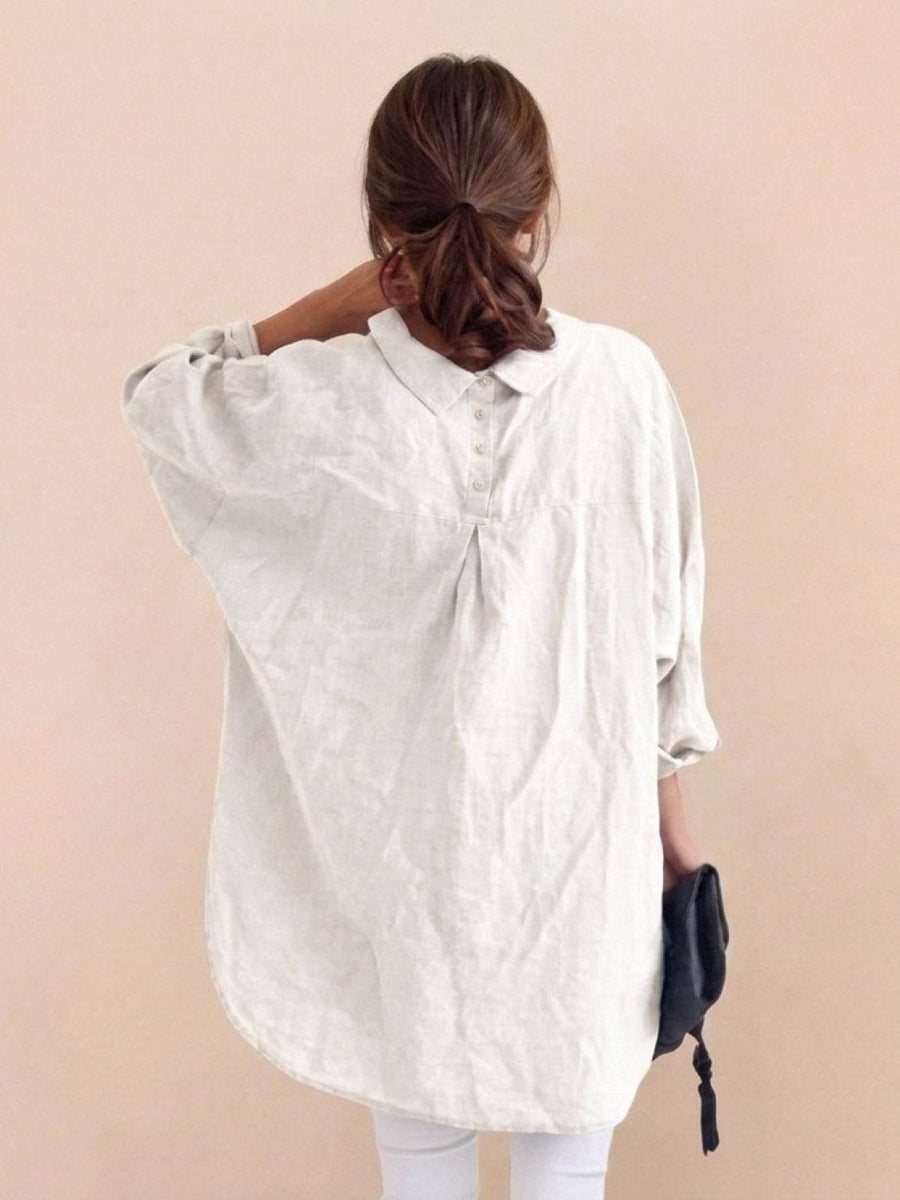Back view of the white oversized linen shirt showing the signature pleat and button detail